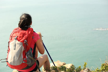 远足女子坐在海边的岩石上