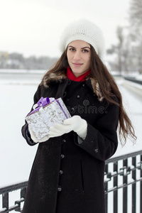 快乐的白种人年轻女人在下雪的天气里拿着一个盒子