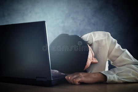 精疲力竭的人睡在办公桌的笔记本电脑上