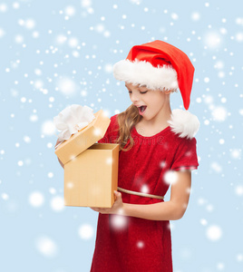 微笑的女孩戴着圣诞老人的帽子和礼品盒