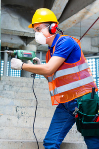 墙壁上的箭头亚洲工人在工地墙壁上钻孔照片