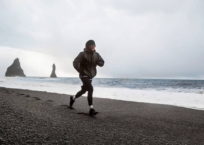 一个运动员在冰岛的黑色海滩上跑步