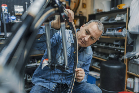 熟练修理自行车的自行车服务。修理过程中的一个车间的自行车技工。时尚的自行车机械师在车间做他的专业工作。