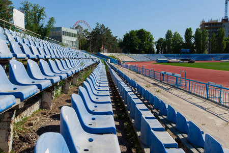 阳光明媚的一天,蓝蓝的天空,蓝蓝的座位在体育场,草地,绿野,跑道上