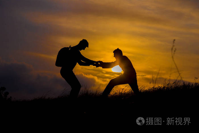 团队合作夫妇徒步旅行互相帮助,信任协助剪影在山上日落 团队合作的