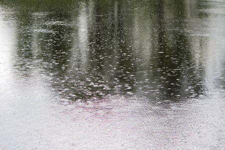 湖面上一场强烈的夏季倾盆大雨。 雨点落在水里。