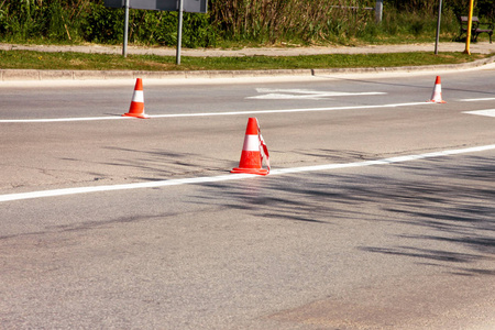 在路上工作。 建筑锥。 沥青上有白色和橙色条纹的交通锥。 街道和交通标志的信号。 在建道路维修标志和道路交通锥。