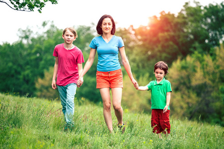 男孩们和妈妈在草地上牵着青草的手.
