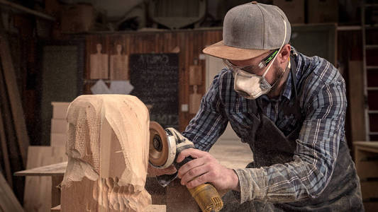 s head with a tree , using an angle grinder  in the workshop, ar