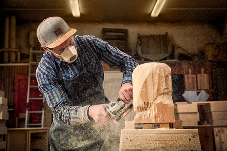 s head with a tree , using an angle grinder  in the workshop, ar