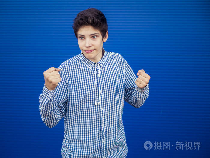一个年轻男子双拳在蓝色背景下被隔离