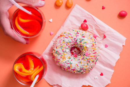 s hand takes sweet pastry. Frosted sprinkled donut on pink backg