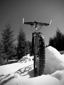 近宽视野的山地自行车停留在雪中。 冬天雪山，树间有路。