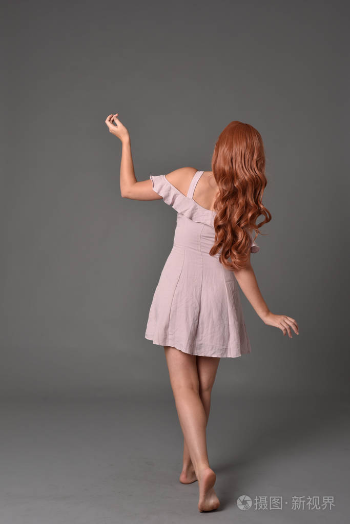 穿粉色夏装的女孩的全长肖像.站姿灰色演播室背景