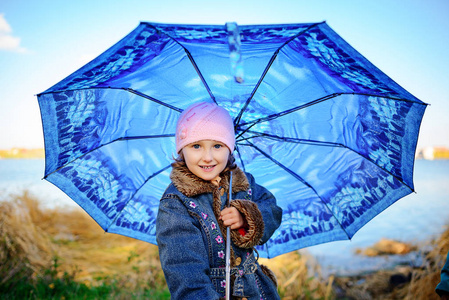 小女孩和男孩带着雨伞在雨中玩耍。 孩子们在秋天的雨天在户外玩耍。 秋天对孩子们的乐趣。 蹒跚学步的孩子穿着雨衣和靴子在花园里散步