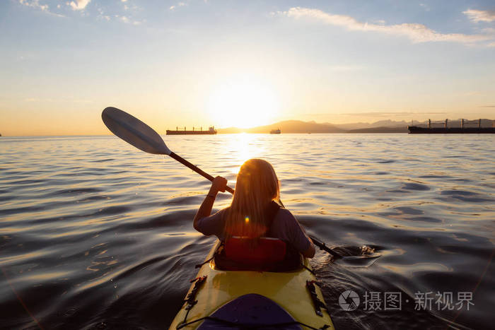 在一个充满活力的日落中皮艇上的女人正在海洋中划船摄于加拿大不列颠