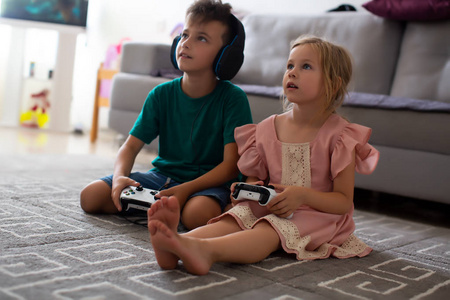 特写兄弟姐妹在家里的地毯上玩视频游戏控制器