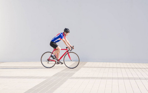 运动员骑自行车骑在六月的自行车背景上的白光墙.