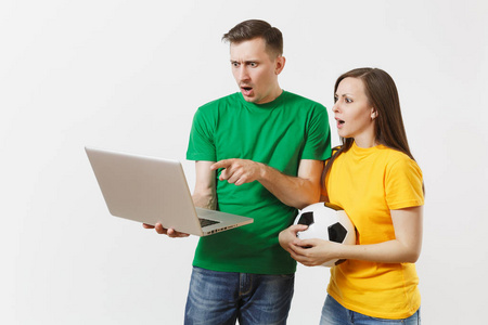 震惊的夫妇，男人，足球迷，穿着黄色的绿色T恤，振作起来，支持队与足球观看比赛的个人电脑笔记本电脑隔离在白色背景。 体育家庭休闲生