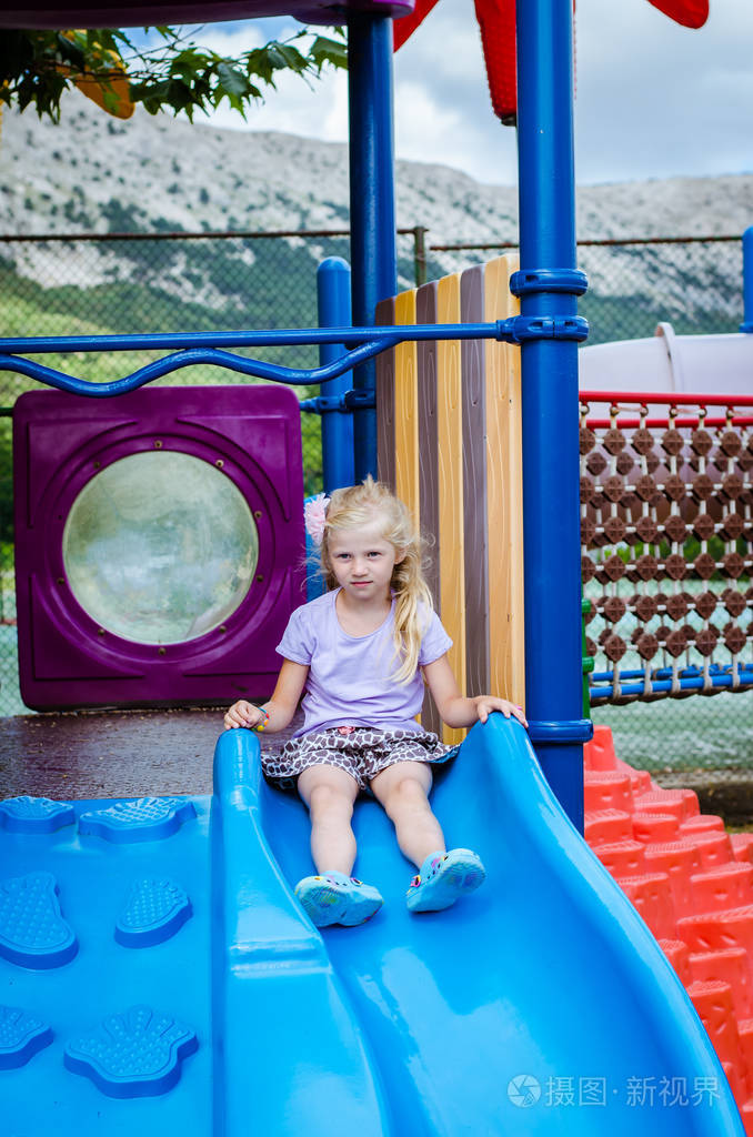可爱的金发小女孩留着长发玩滑滑梯