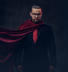 一个天才超人的肖像在黑色的西装与红色领带在黑暗的背景