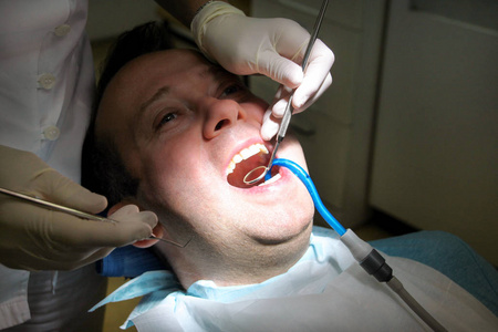 牙科检查。 牙科检查与牙科工具，探头镜和吸管在口腔。 牙医正在牙科诊所和办公室检查病人的牙齿。 牙科口腔卫生。 牙医的概念。