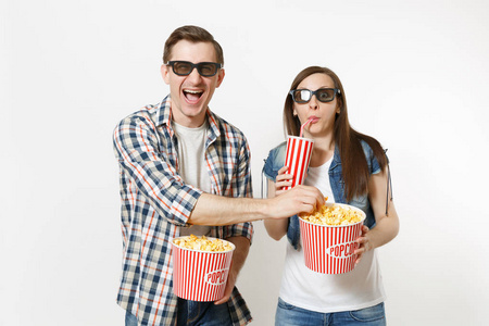 年轻的笑对夫妇，戴着3D眼镜看电影，约会时拿着一桶爆米花，塑料杯，苏打水或可乐，偷吃白色背景上的爆米花。 电影中的情绪