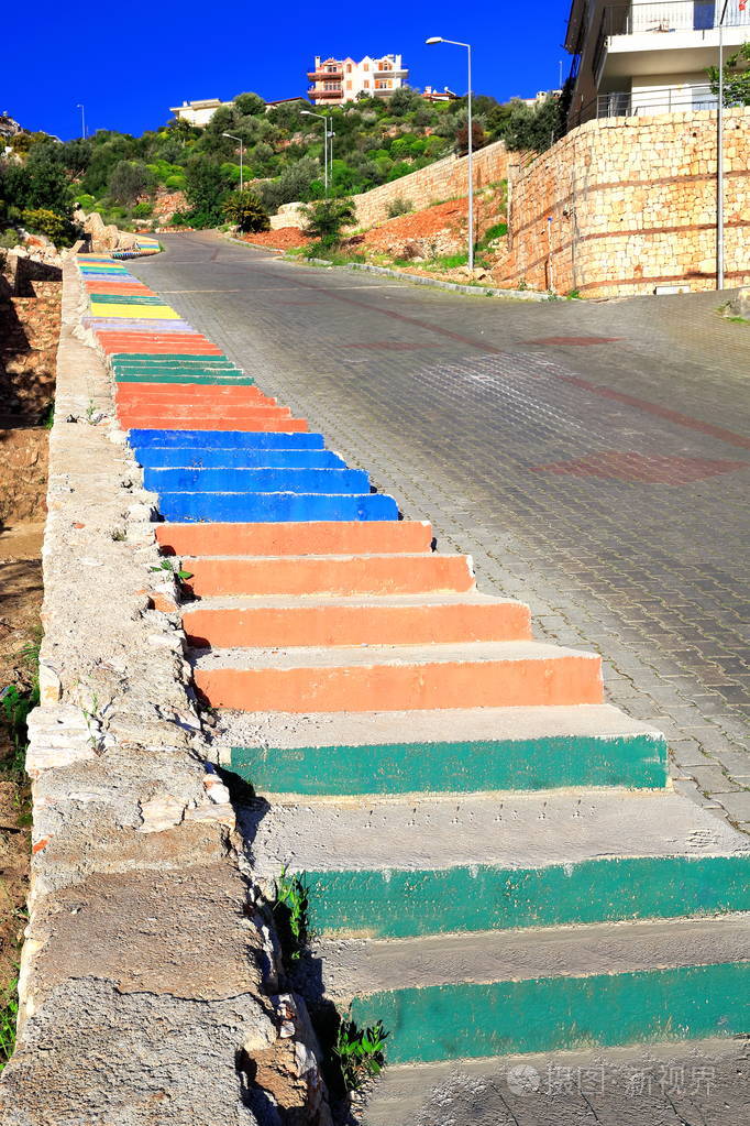 一条陡峭的鹅卵石街道的人行道上,一个混凝土楼梯的多色油漆台阶,连接