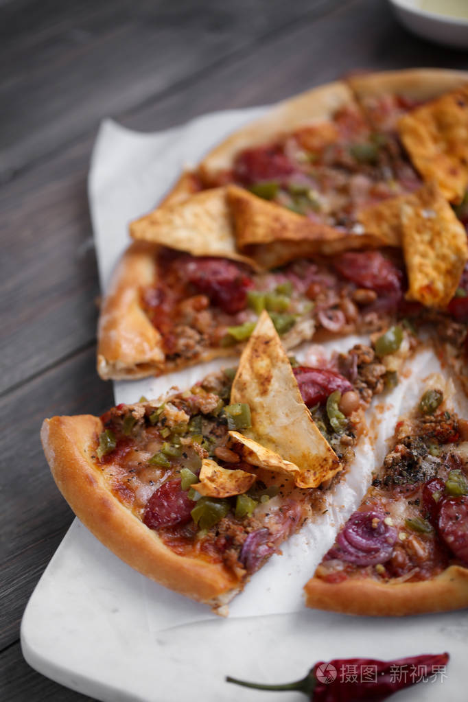 墨西哥比萨饼与薯条,洋葱,热辣胡椒在薄的经典面团. 切片的特写照片.