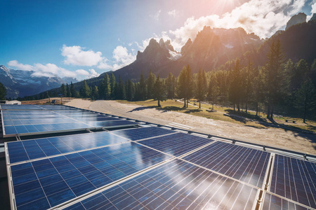 太阳能电池面板在乡村景观与阳光明媚的天空和山脉背景。 太阳能是世界能源可持续性的创新。 可持续资源。