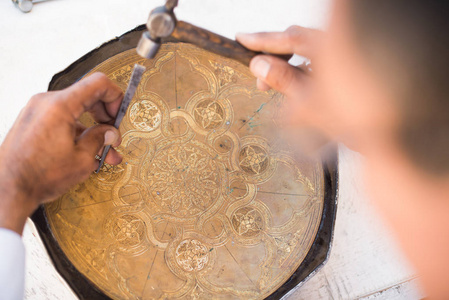 工匠在托盘上雕刻图案。 中亚的主人。 手工铸铜