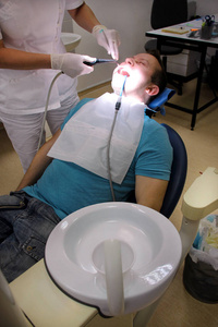 用于冲洗牙齿的牙科工具。 牙齿清洁牙齿卫生。 牙科医生在他的牙科诊所和办公室工作，正在用镜子清洁工具喷雾和口腔吸管冲洗病人的牙齿