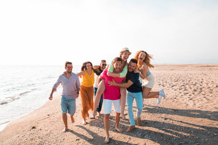 多文化的朋友团体在海滩上聚会，年轻人在暑假暑假和假日期间庆祝