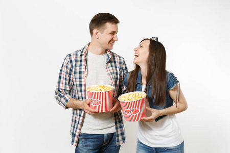 年轻快乐的微笑夫妇，女人和男人，戴着3D眼镜和休闲服，看电影，约会时拿着一桶爆米花，在白色背景上笑得很孤立。 电影概念中的情感