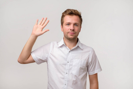 英俊迷人的欧洲男人挥手打招呼,同时愉快地微笑.