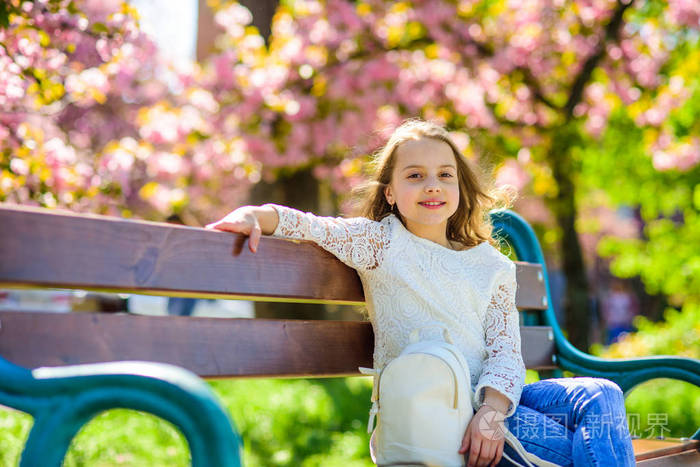 在樱桃花附近公园散步的女孩放
