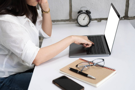 年轻的商务女性使用笔记本电脑与空白桌面屏幕手按键盘在家庭办公室。 模拟女性手连接社交媒体社交网络和营销。