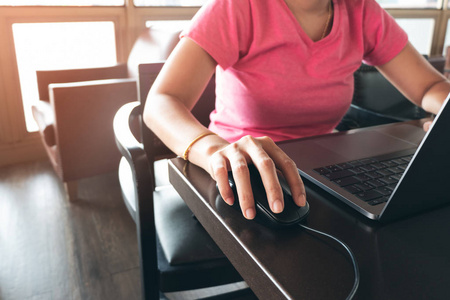 关闭年轻的自由职业女性手与笔记本电脑在桌子上，点击鼠标和打字，而坐在咖啡馆。 商务女性穿休闲服装，在网上工作，学习连接互联网。