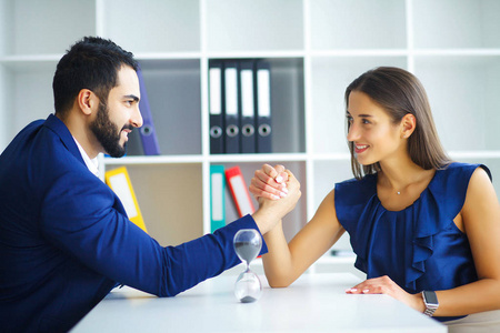 生意. 商务女性和商务男性坐在桌子旁的轻型办公室里交谈.