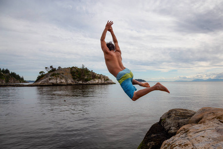冒险的人是悬崖，从岩石跳到海洋。 在加拿大温哥华西部的Whytecliff公园马蹄湾。