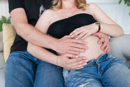 怀孕的夫妇抱着女人的腹部靠近。 紧紧抓住人类夫妇的手，抱着怀孕的肚子。 丈夫温柔地拥抱怀孕的妻子。 恩爱夫妻