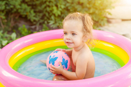 孩子们在充气婴儿池玩耍。孩子们在五颜六色的圆水池里游泳和飞溅快乐的小女孩在炎热的夏日里玩水玩具。家庭有乐趣在室外在后院