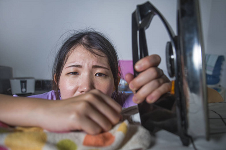 年轻漂亮的沮丧和压力亚洲女人拿着熨斗在家工作，厨房熨烫衣服，绝望和不知所措在家女佣服务，家务，家务压力