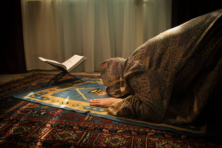 穆斯林妇女在窗户附近的房间里为真主祈祷.