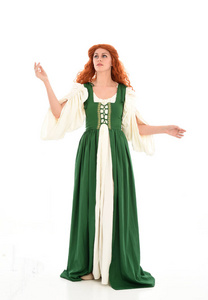全长肖像，红头发女孩，穿着绿色中世纪长袍站姿。 孤立在白色工作室背景上。