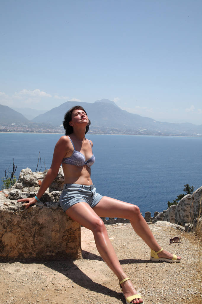 从阿拉尼亚半岛俯瞰阿拉尼亚港。 土耳其里维埃拉。 美丽的女孩在大海的背景上为相机摆姿势。 模特在夏天在海滩上摆姿势。