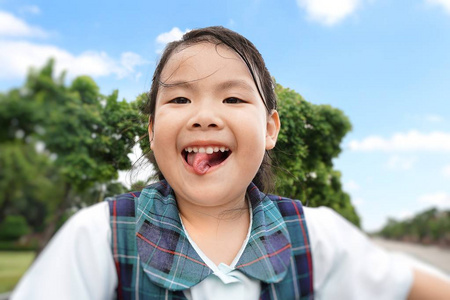 可爱的亚洲小女孩站在天窗上，背景是云树和蓝天。夏日里可爱的孩子微笑着，快乐着。度假度假家庭旅行的理念。
