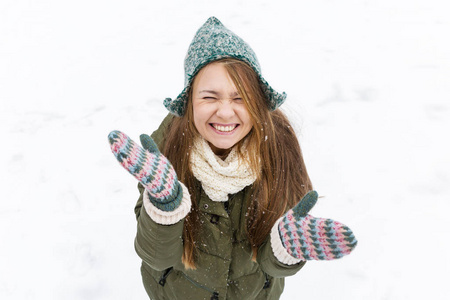 一个金发的年轻漂亮女孩喜欢第一场雪。 绿色夹克，绿色帽子和手套。 上面的风景。 复制空间。