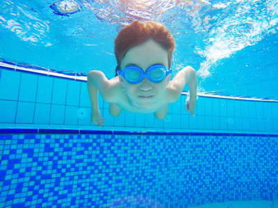 快乐的小男孩游泳和潜水水下孩子蛙泳与乐趣在游泳池。 积极健康的生活方式，水上运动活动和课程与父母在暑假家庭假期与孩子。