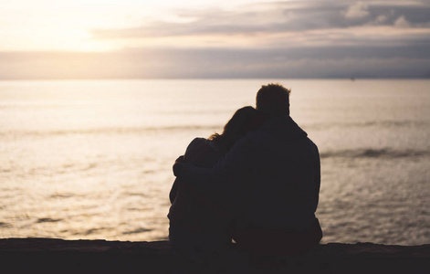 动漫情侣看太阳情侣拥抱背景沙滩海洋日出约会情侣概念剪影两个浪漫的